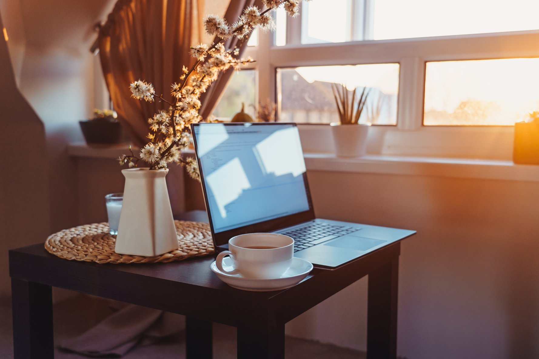 Home Workplace with Laptop, Cup of Tea and Sunset View
